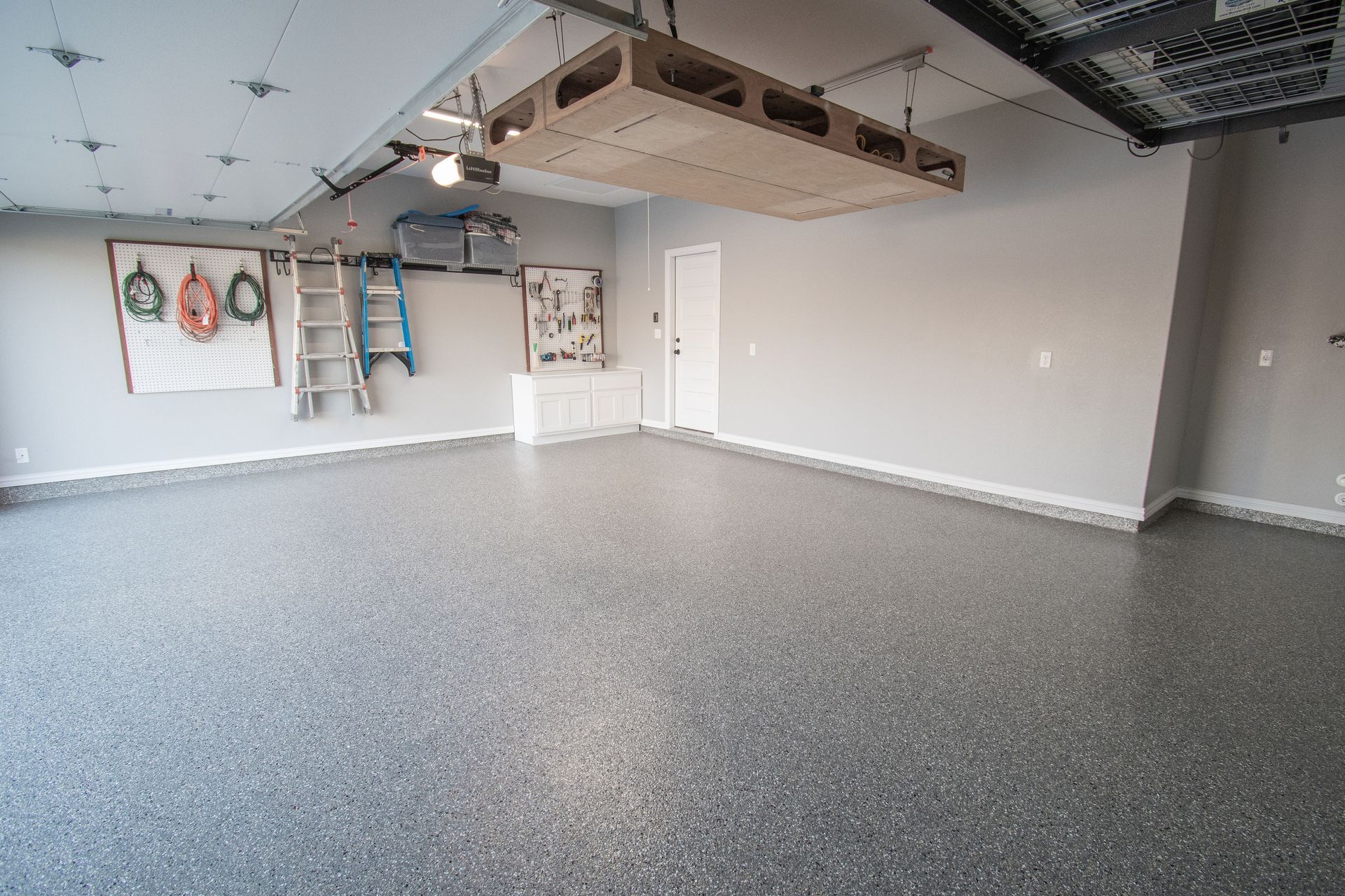 a large empty garage with a ladder hanging from the ceiling