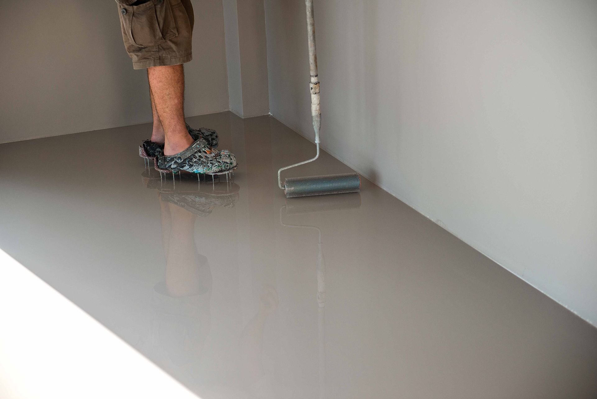 a person is painting a floor with a roller .