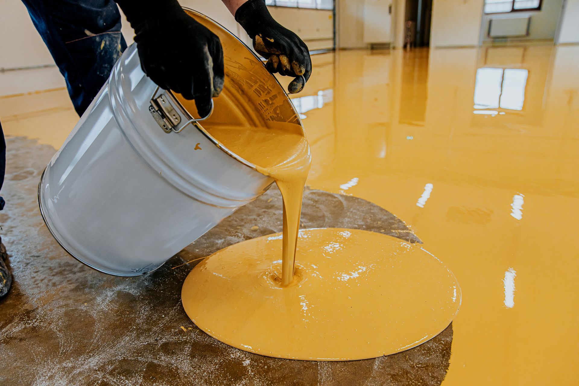a person is pouring yellow paint into a bucket .