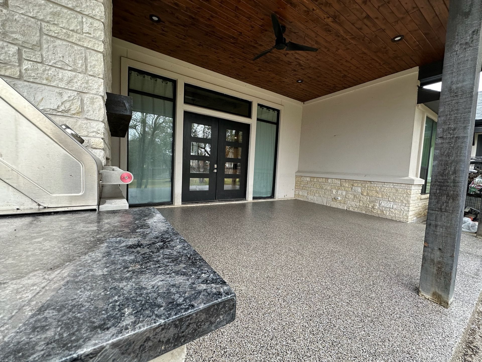 a patio with a ceiling fan and a stainless steel grill .