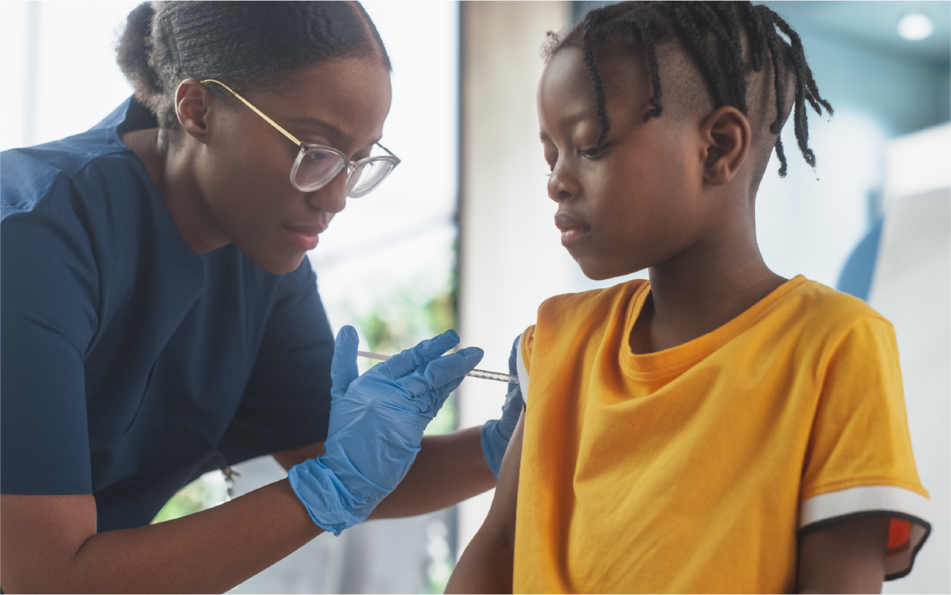 Healthcare worker in blue gloves checks a child’s arm while seated in a bright clinic.
