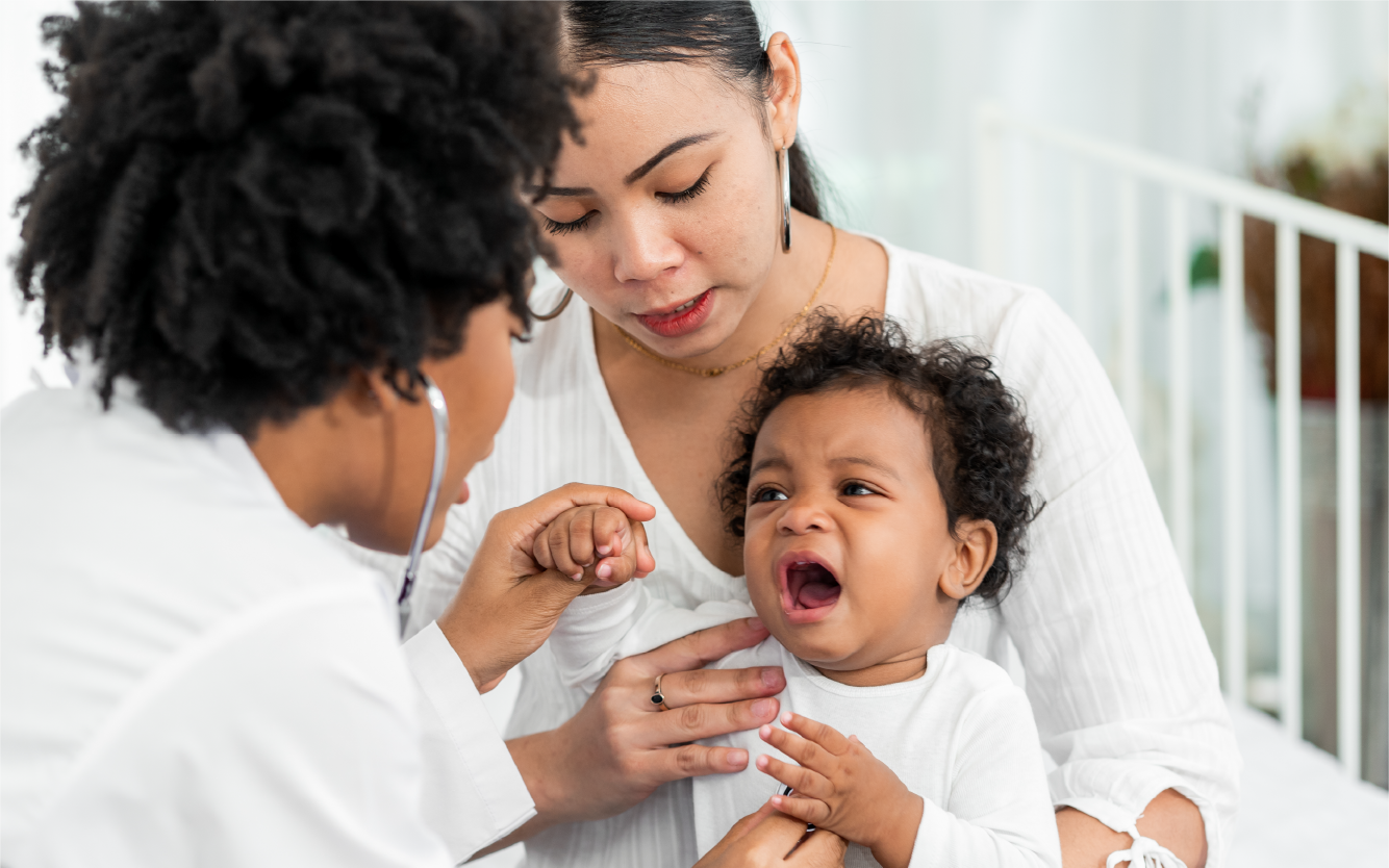 Doctor examining a crying baby while a parent holds them outdoors on a porch