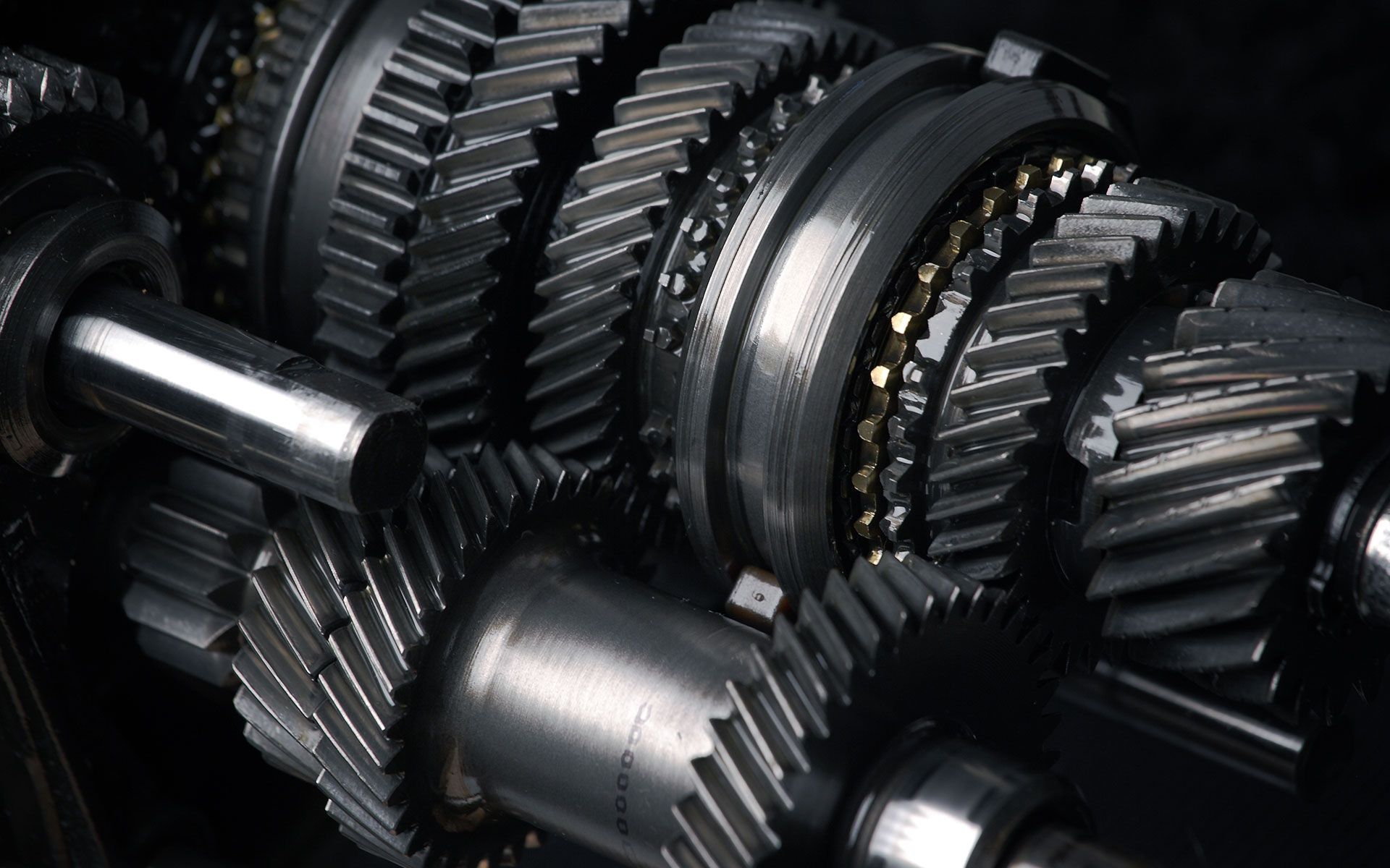 Close-up of a complex mechanical system of gears, shafts, and other components in silver and grey tones.