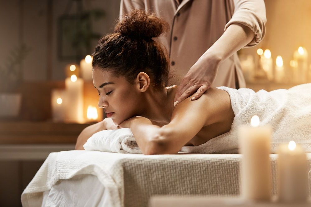 Woman receiving a massage on a table in a candlelit spa room
