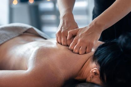 Massage therapist pressing hands into a client’s bare back during a spa treatment