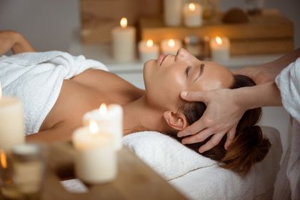 Person receiving a spa massage on a treatment table, surrounded by soft candlelight and towels