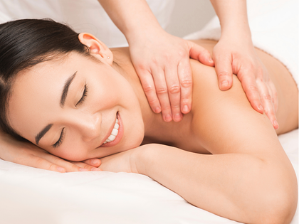 Person receiving a back massage with a handheld device on a spa table