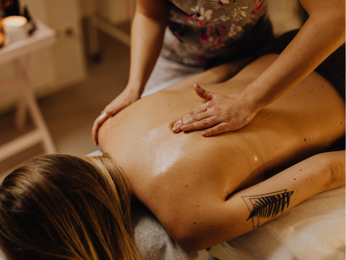 Person receiving a spa massage on a treatment table, surrounded by soft candlelight and towels