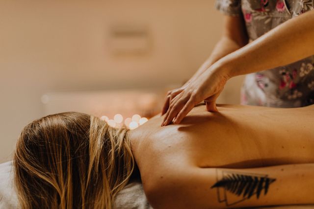 Massage therapist kneading a client’s bare back in a warm spa setting