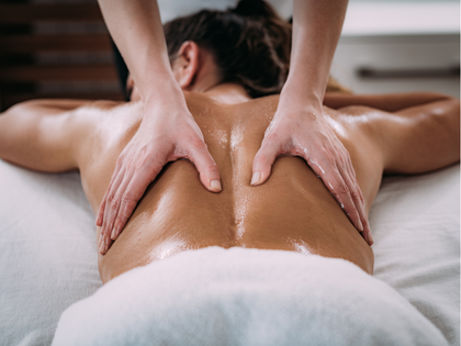 Person receiving a back massage with a handheld device on a spa table