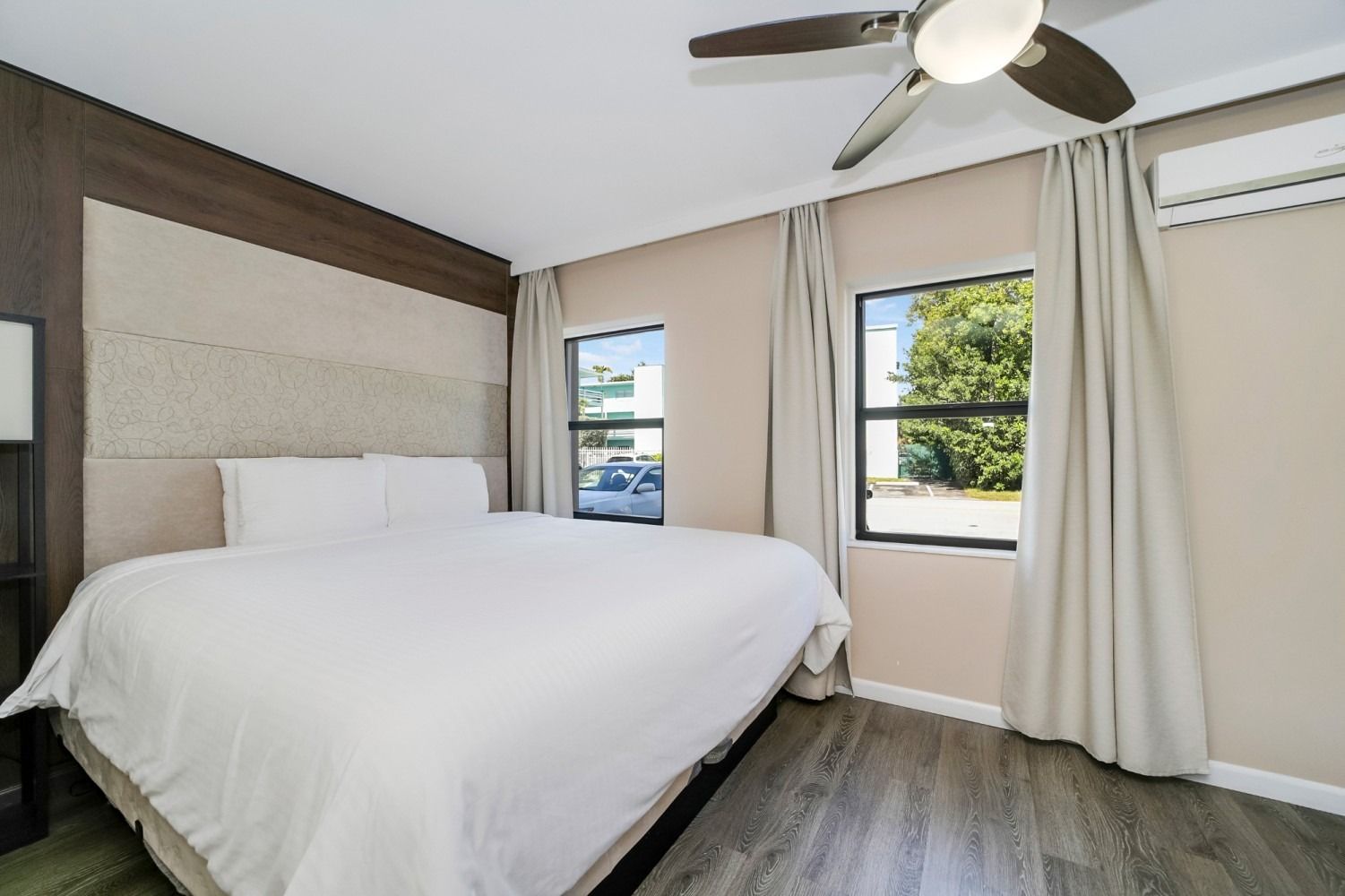 Bedroom with bed, windows, ceiling fan, and air conditioner.