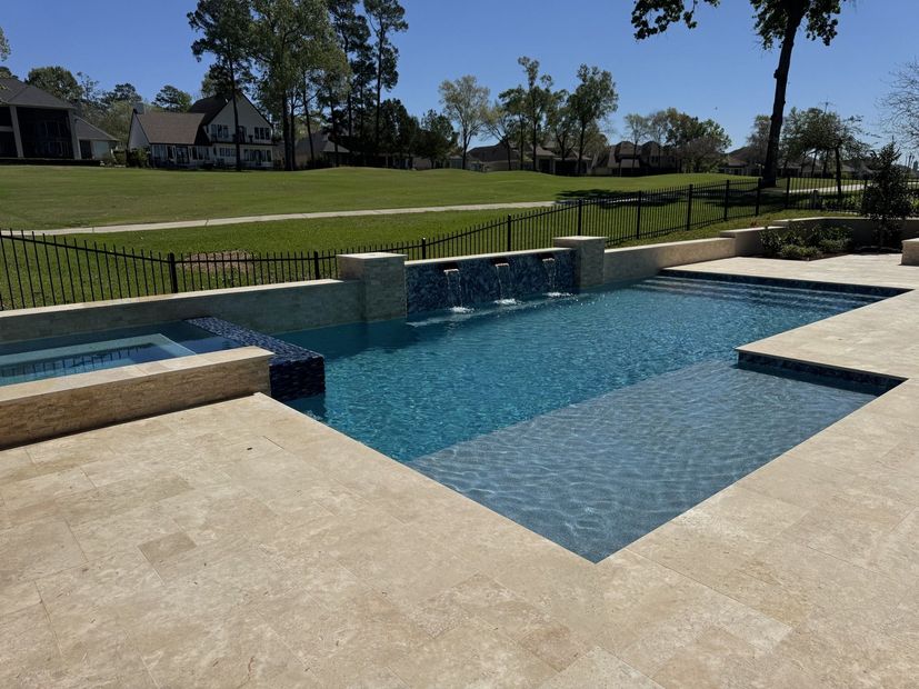 Backyard pool and hot tub overlooking a lake, with a lawn and dock in the background
