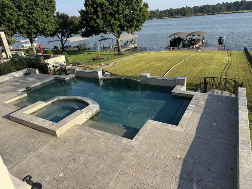 Backyard pool and hot tub overlooking a lake, with a lawn and dock in the background
