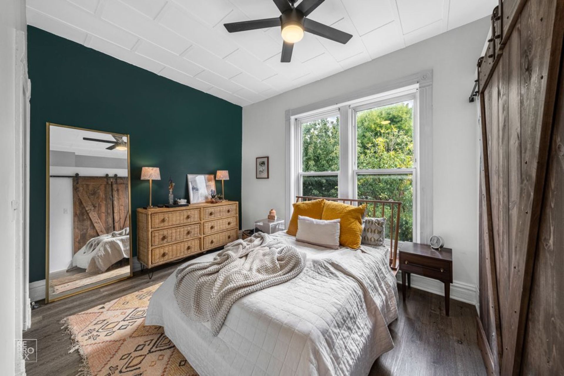 A bedroom with a bed , dresser , mirror and ceiling fan.