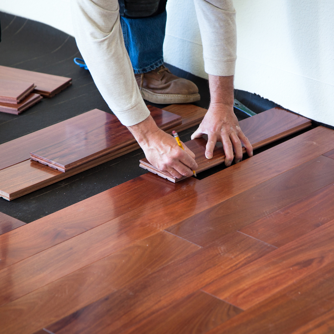 A person is installing a wooden floor in a room.