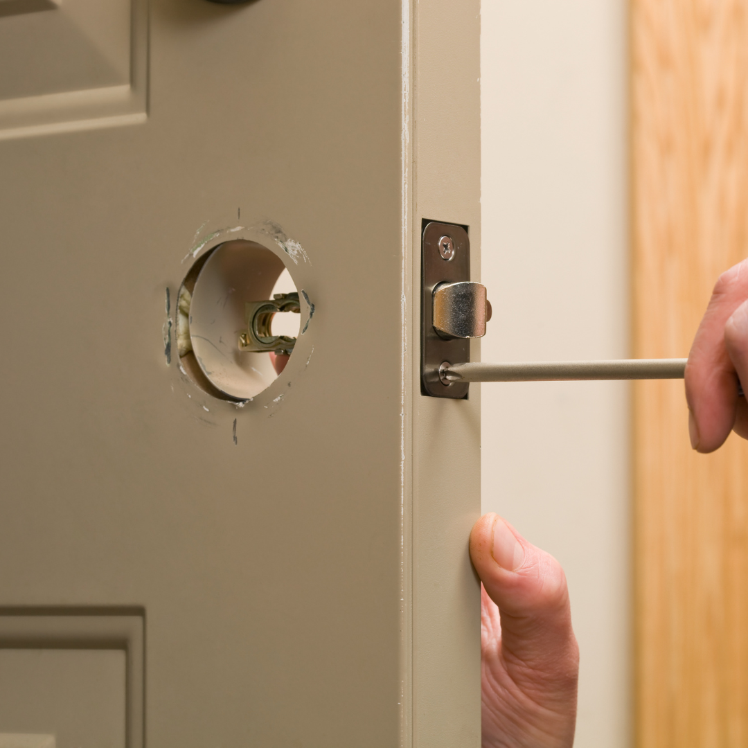 A person is fixing a door with a screwdriver.