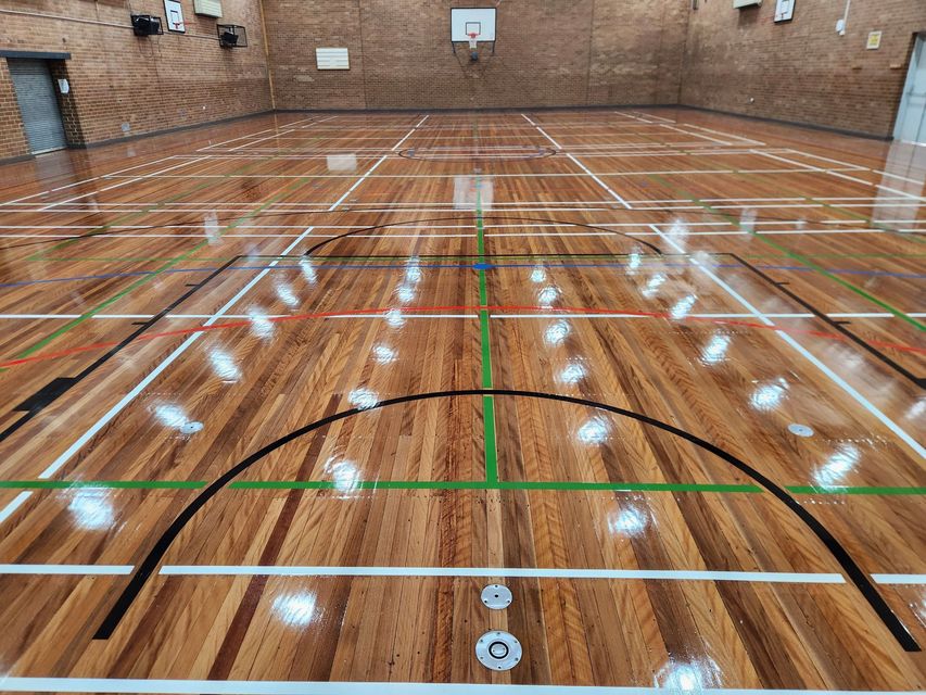 Empty indoor basketball court with polished wood floor and court lines