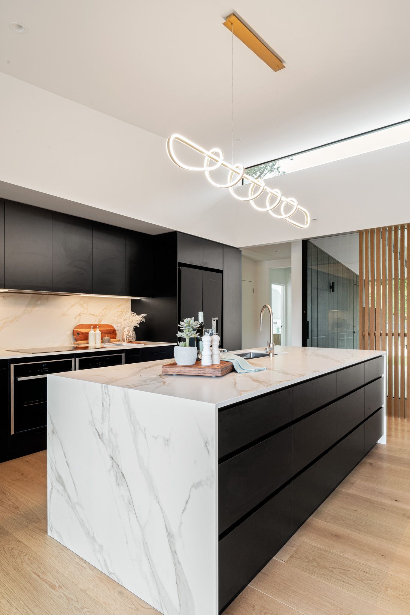 Modern kitchen with a marble island, black cabinetry, and pendant lighting