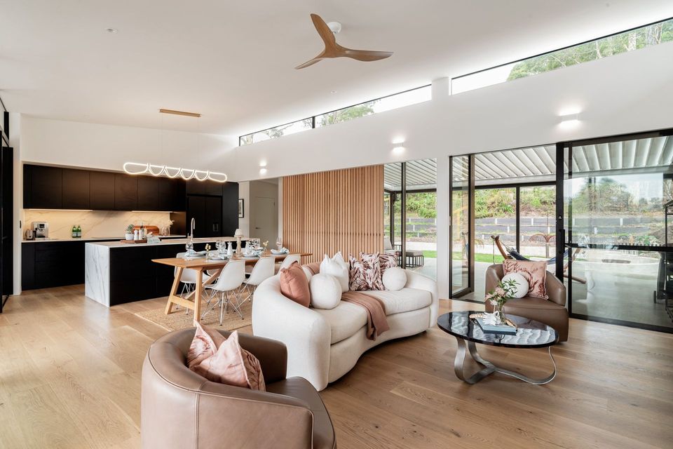 Bright modern living room with beige sofas, wood floors, and large glass doors to a patio