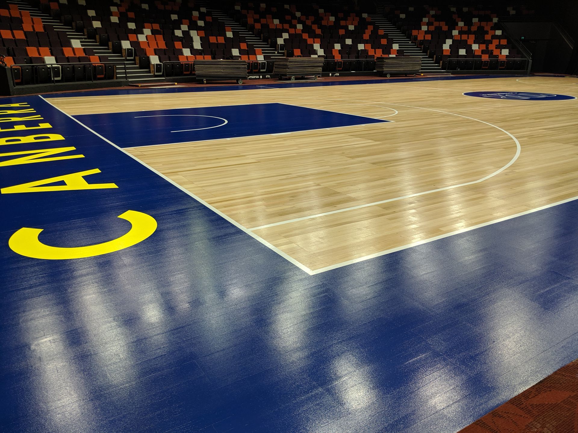 Empty basketball court with blue-painted sidelines and yellow lettering in an arena Empty basketball court with blue-painted sidelines and yellow lettering in an arena