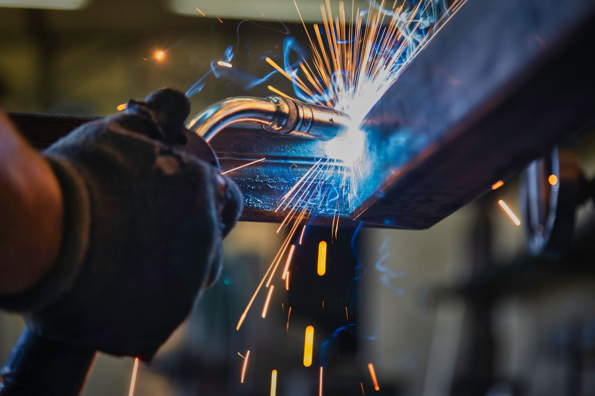 A person is welding a piece of metal in a factory.