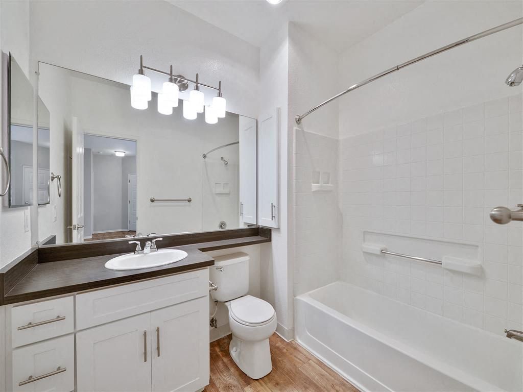Bathroom in an apartment with a vanity, toilet, and tub/shower with grab bars at Rosewalk Apartment Homes in San Jose, CA.