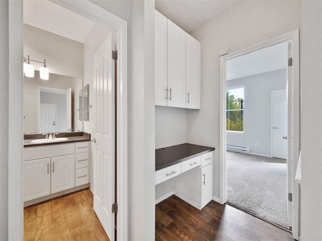 Interior view of a small apartment with a built-in desk and a bathroom doorway at Rosewalk Apartment Homes in San Jose, CA.
