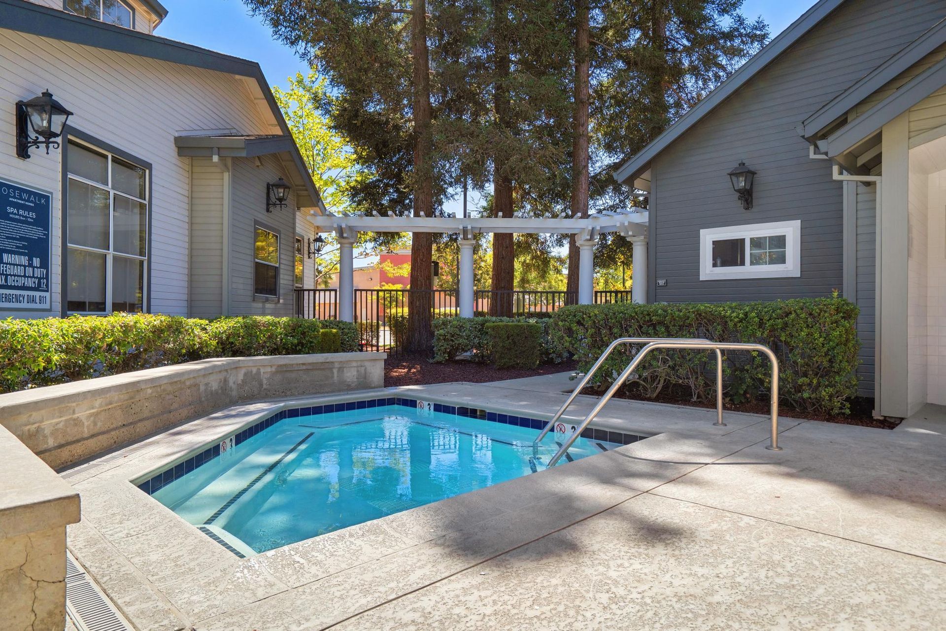 Courtyard pool between two gray buildings with blue water and a metal handrail