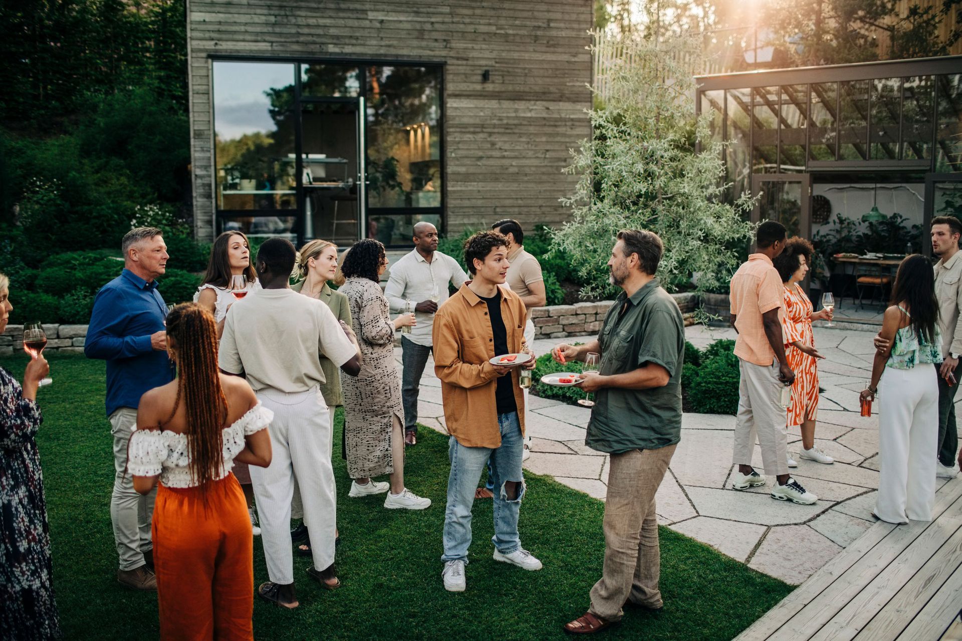 A group of people are standing outside of a house talking to each other.