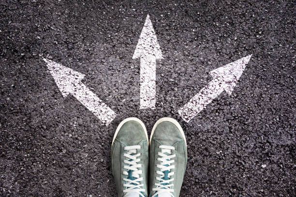 A pair of shoes standing in front of three arrows on the ground.