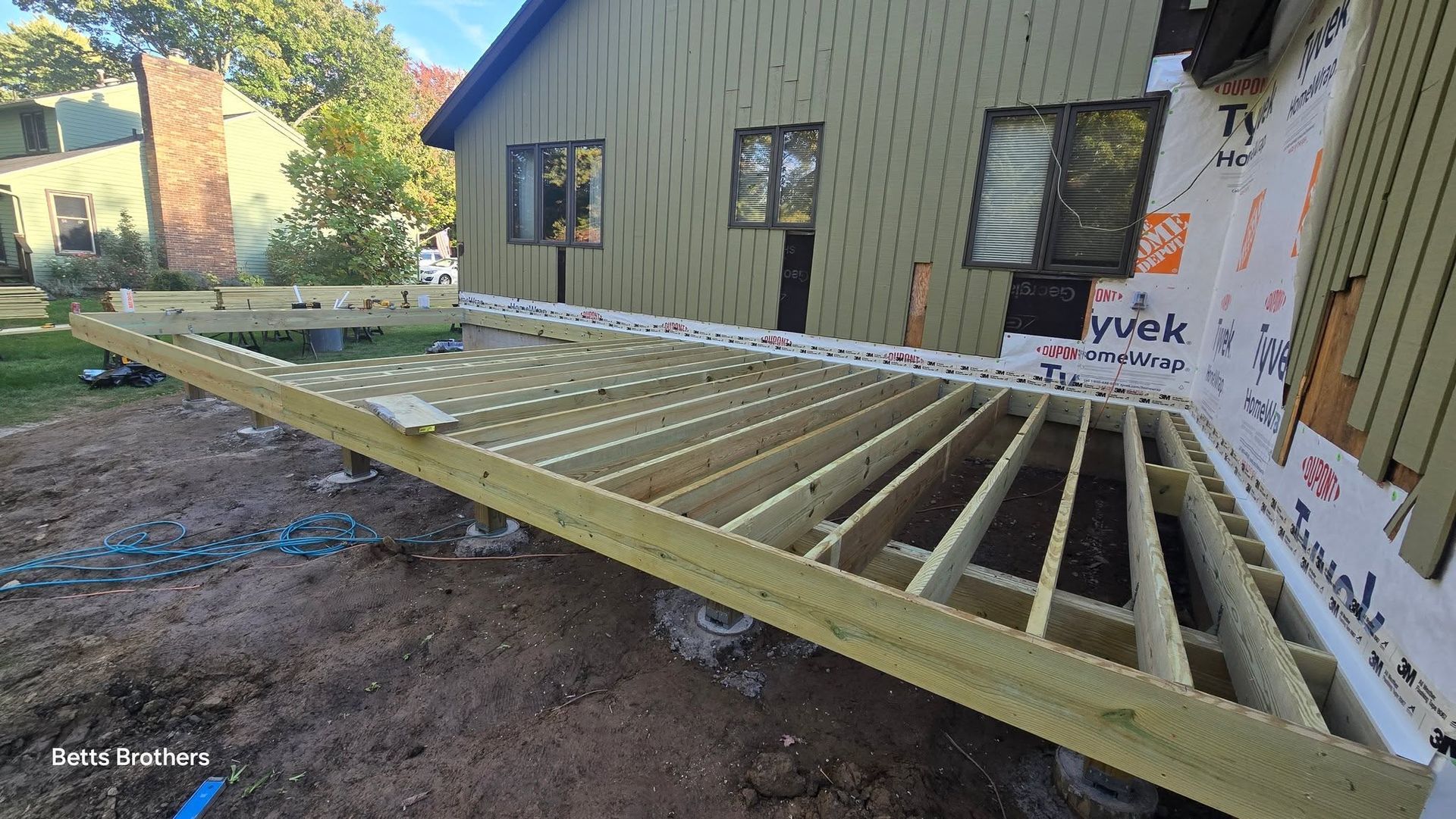 Partially built wooden deck frame beside a house under construction