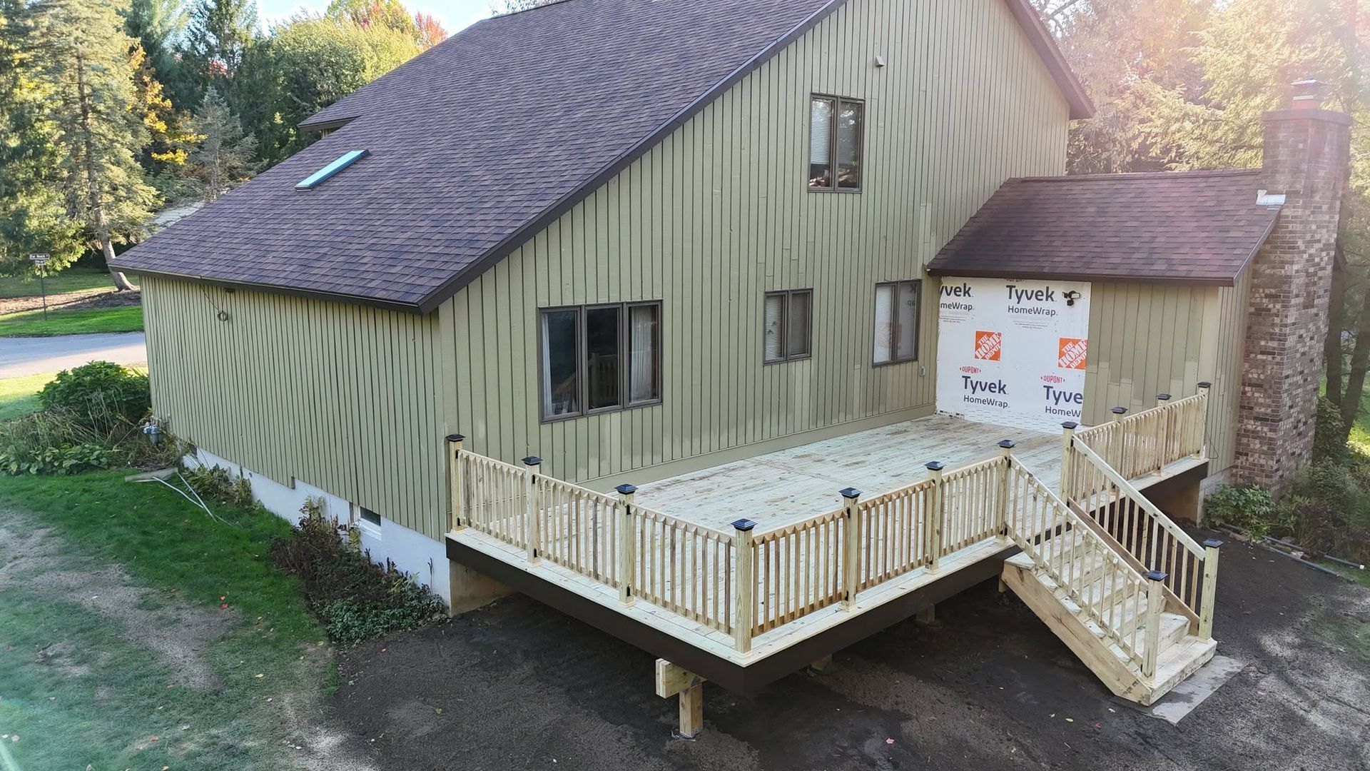 Small green house with a new wooden ramp and porch under construction in a yard