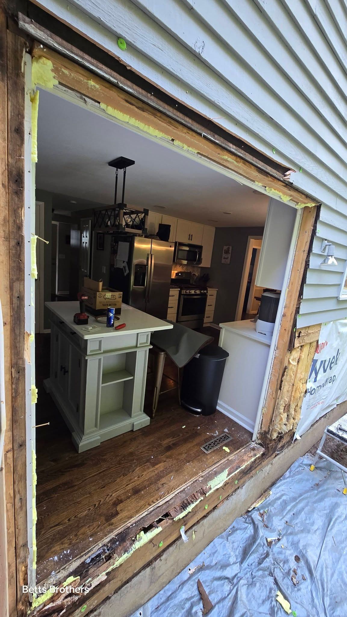 Open garage doorway showing a kitchen with cabinets, island, and hanging lights inside a home