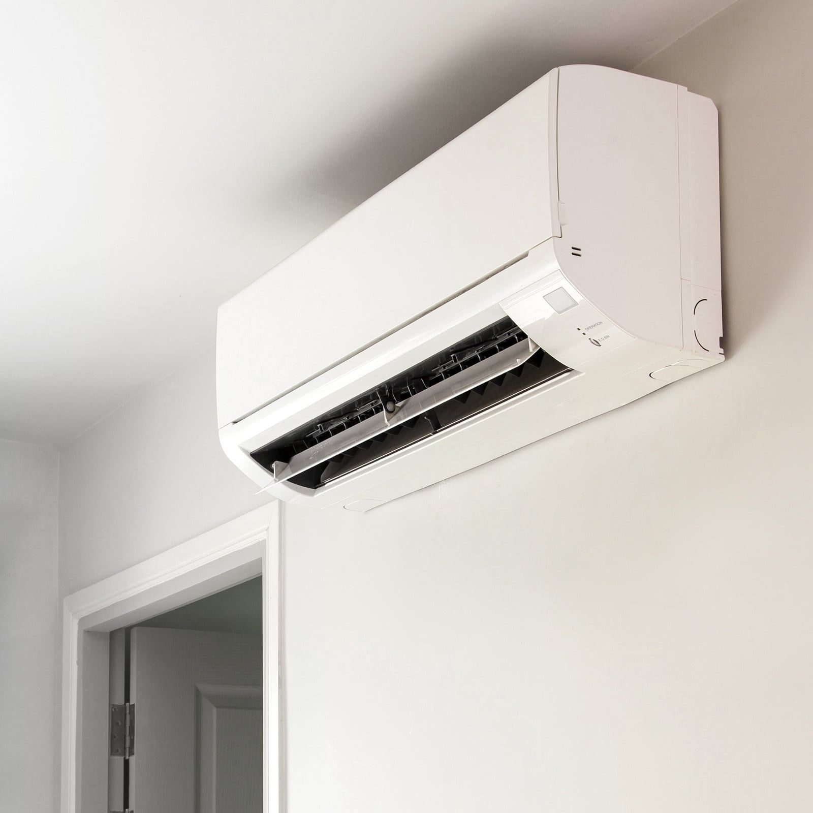 White wall-mounted air conditioner above a doorway in a bright room
