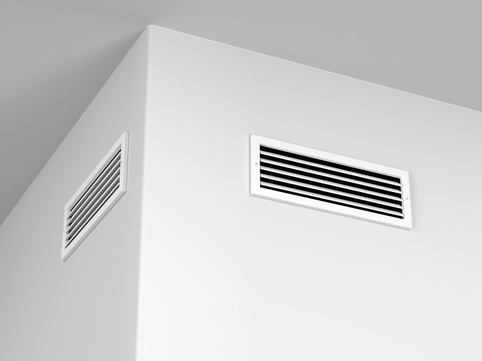 White wall corner with two rectangular air vents near the ceiling