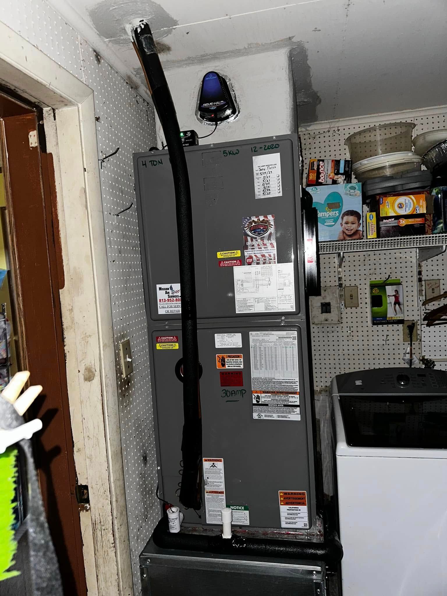 Gray refrigerator in a cluttered kitchen, with a black pipe attached and magnets and notes on the door.