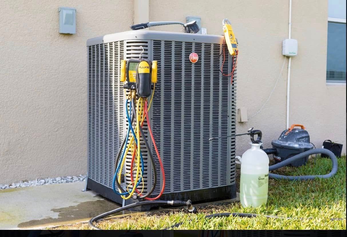 Outdoor air conditioner unit with hoses and a refrigerant tank beside it