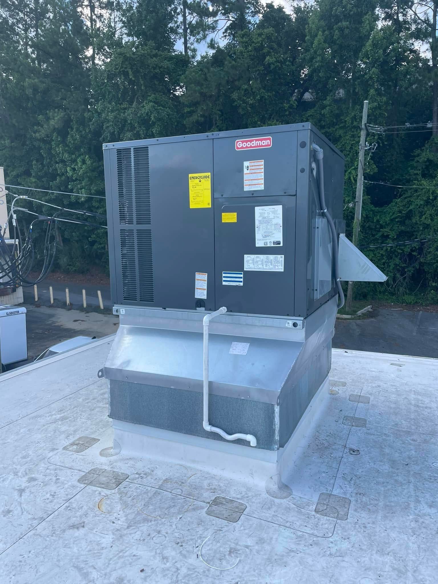 Large gray HVAC unit on a rooftop, with warning labels and trees in the background.