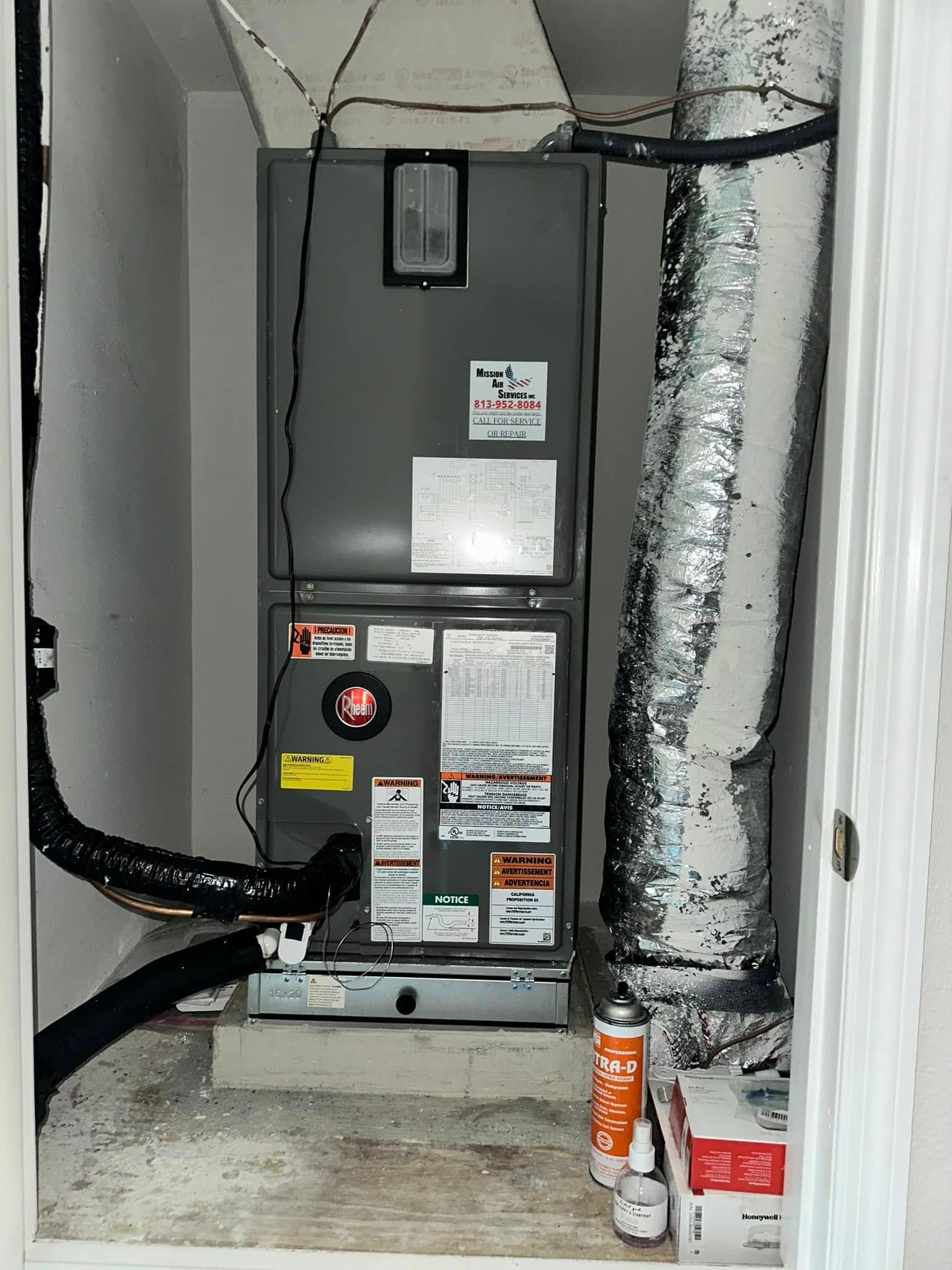 HVAC furnace in a narrow utility closet with exposed ducts and insulation, one panel open.