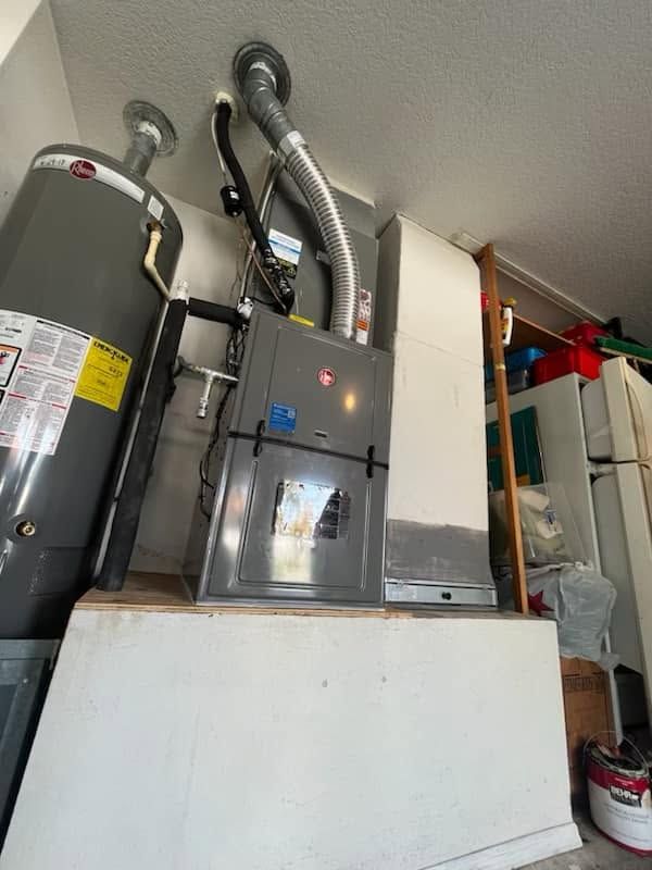 Utility room with furnace, water heater, and HVAC ducts along a basement wall