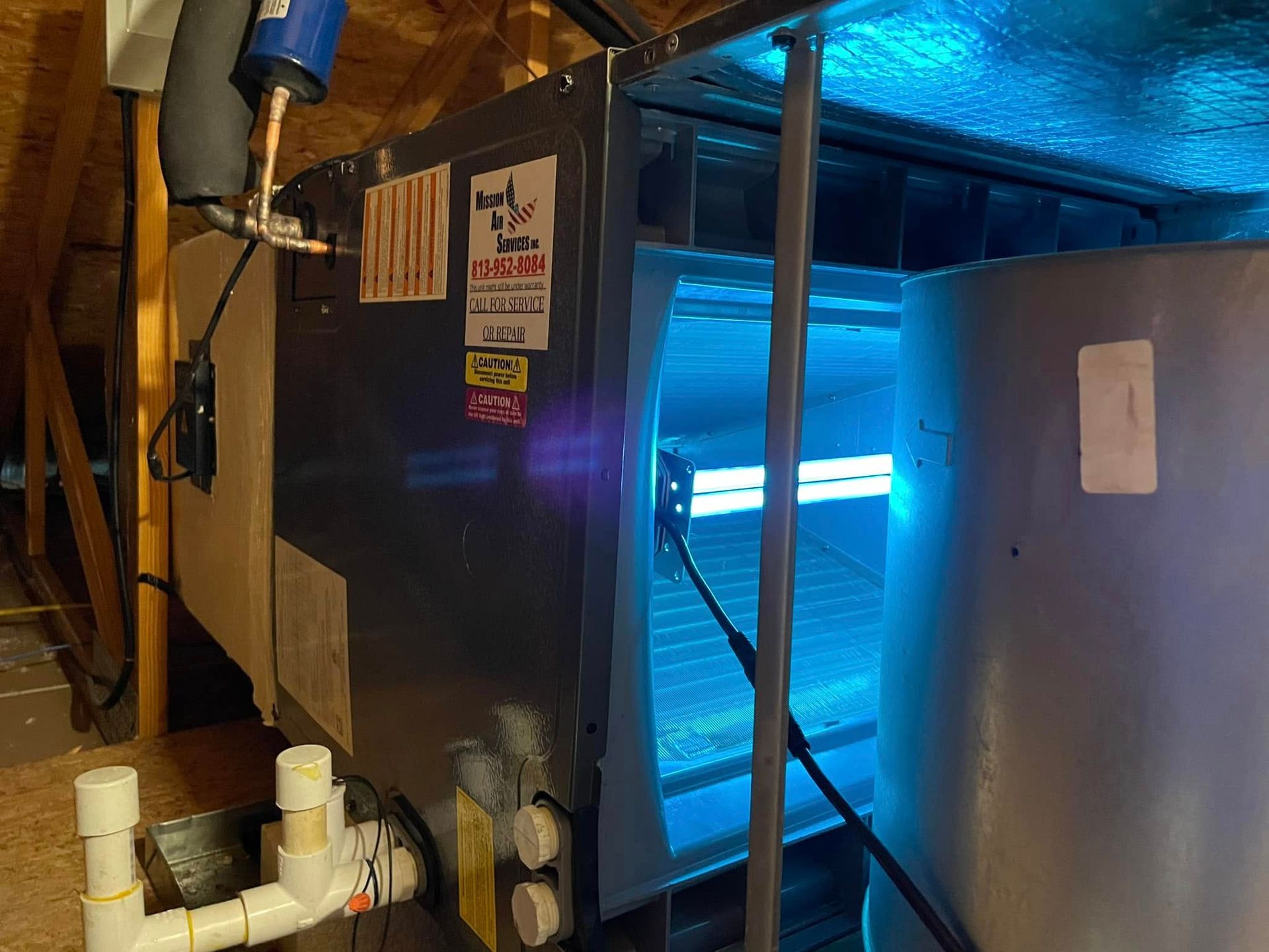 Blue-lit industrial machine in a workshop, with metal ducting and pipes nearby