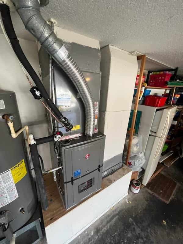 Residential furnace and HVAC unit with silver ducting and pipes in a utility closet