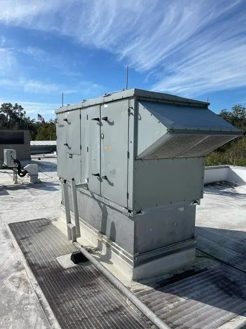 Industrial rooftop HVAC unit under a blue sky on a flat roof