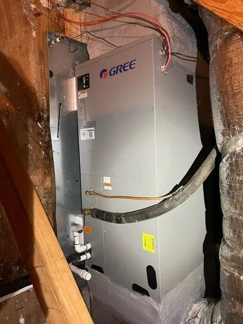 Gray Gree HVAC unit installed in an attic with exposed wood framing and wiring