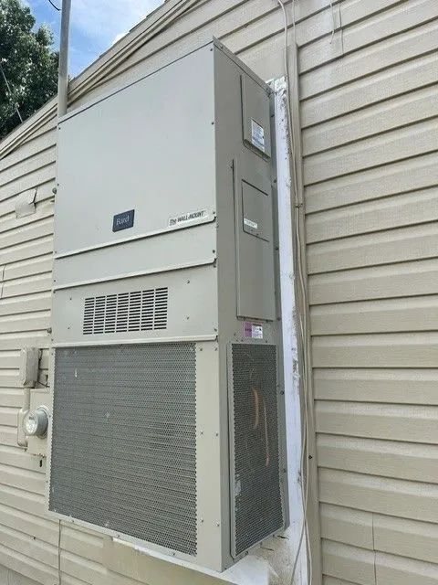 Outdoor wall-mounted HVAC unit beside beige siding and a downspout