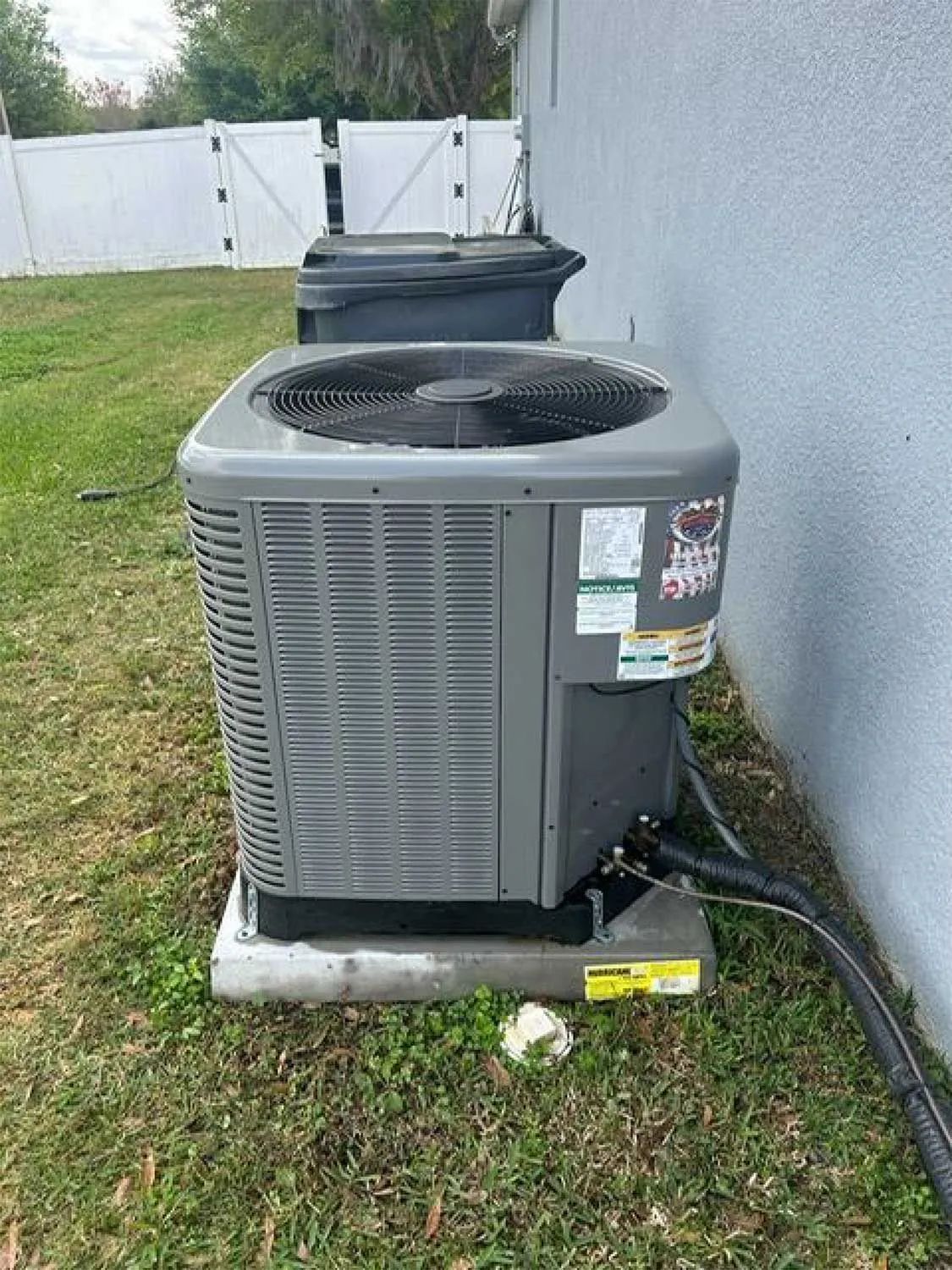 Outdoor central air conditioning unit beside a house on a grassy lawn.