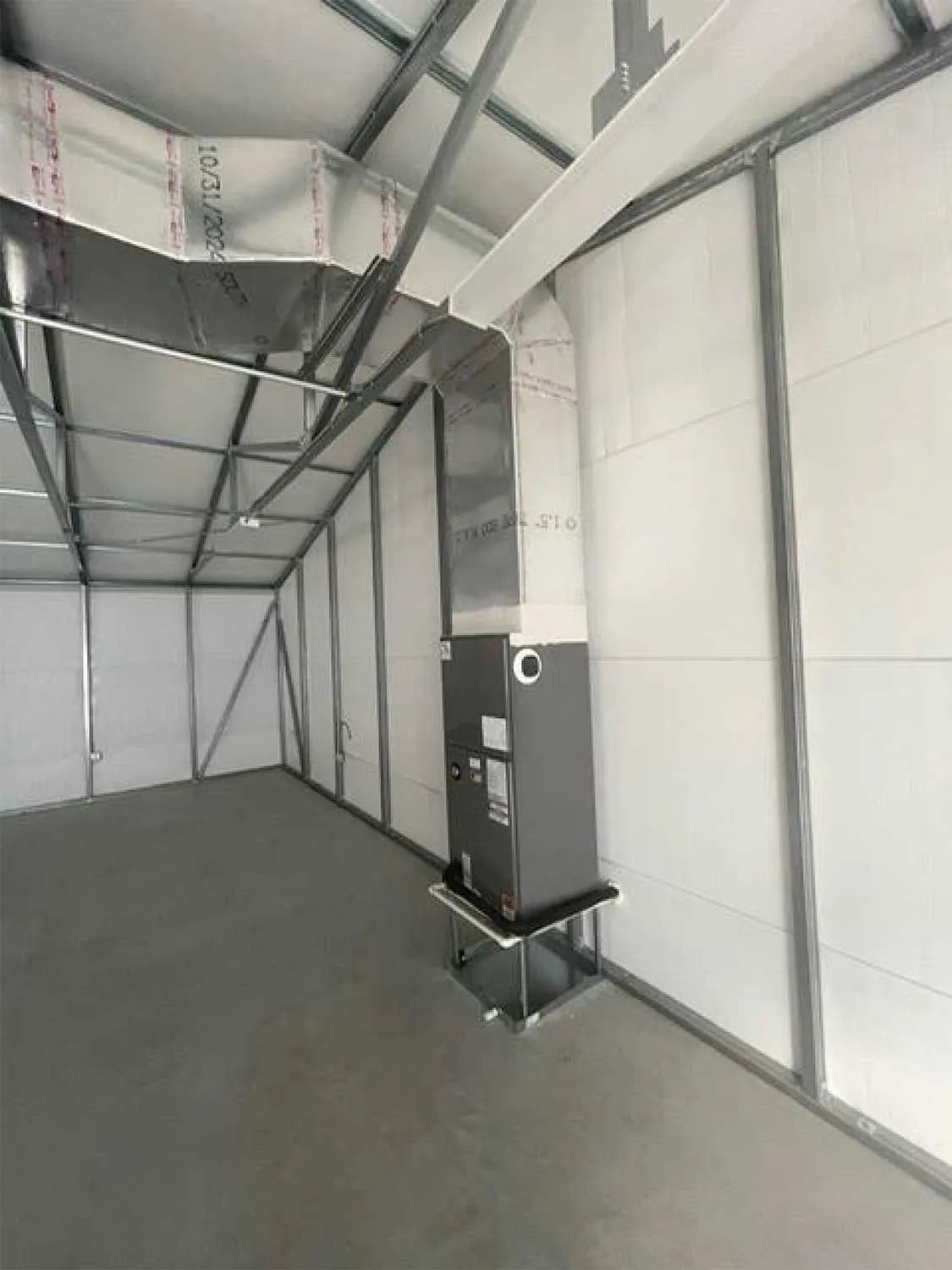 Empty white tent interior with metal framing and a black heater unit on the right side
