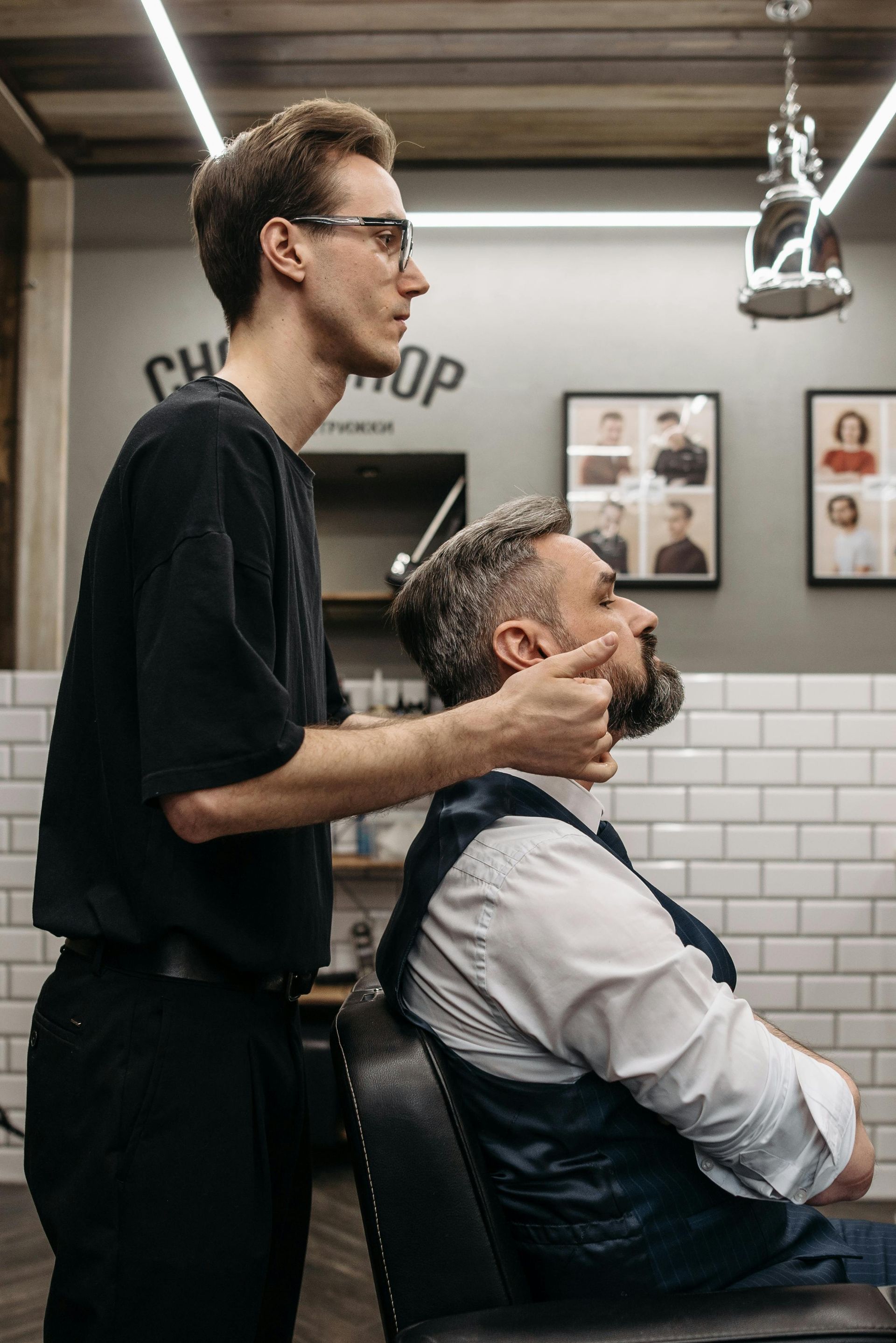 Barber trimming a seated client’s beard in a modern barbershop