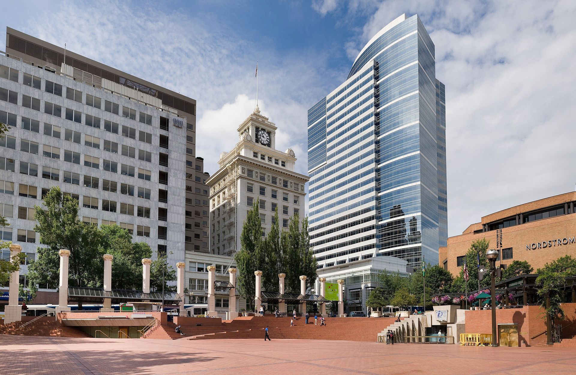 Pioneer Courthouse Square in Portland, Oregon, with several buildings, including a modern glass skyscraper. Sunny day.