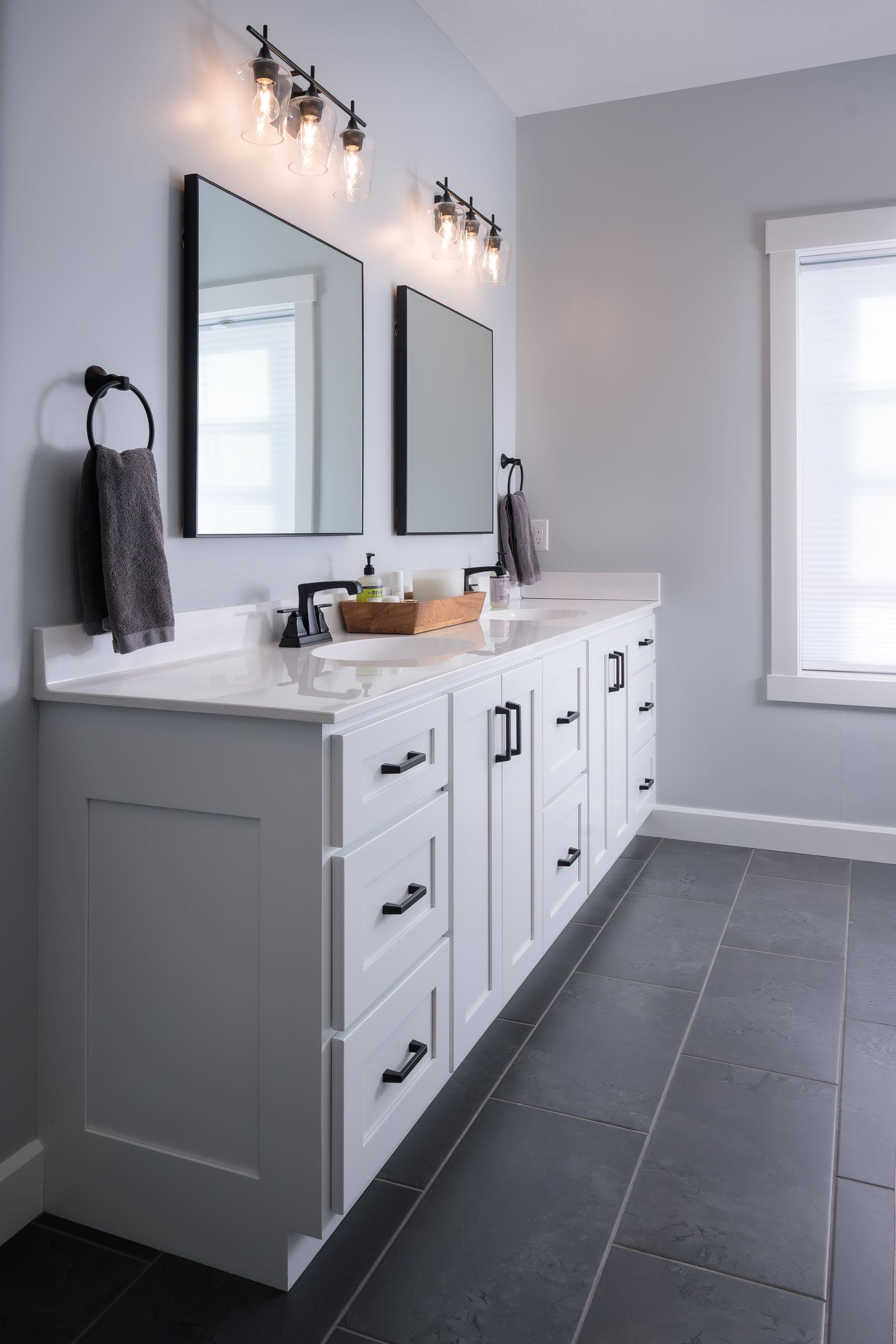 Custom white painted wood double bathroom vanity and dark floor.